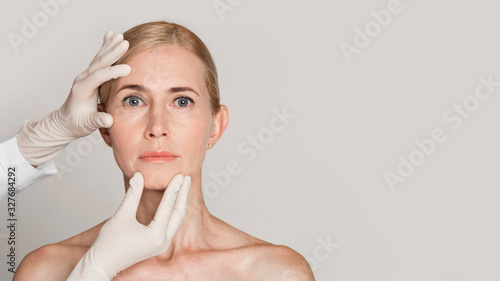 Dermatologist touching face of beautiful mature woman