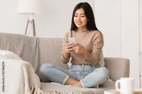 Cheerful girl texting on smartphone, enjoying weekend