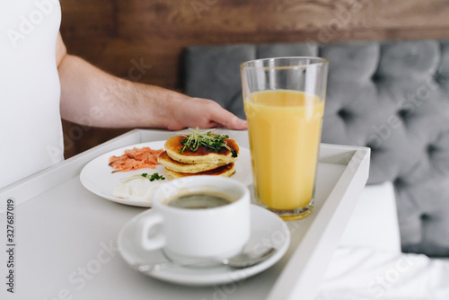 Caucasian man hands, bringing tasty breakfast to bed on tray