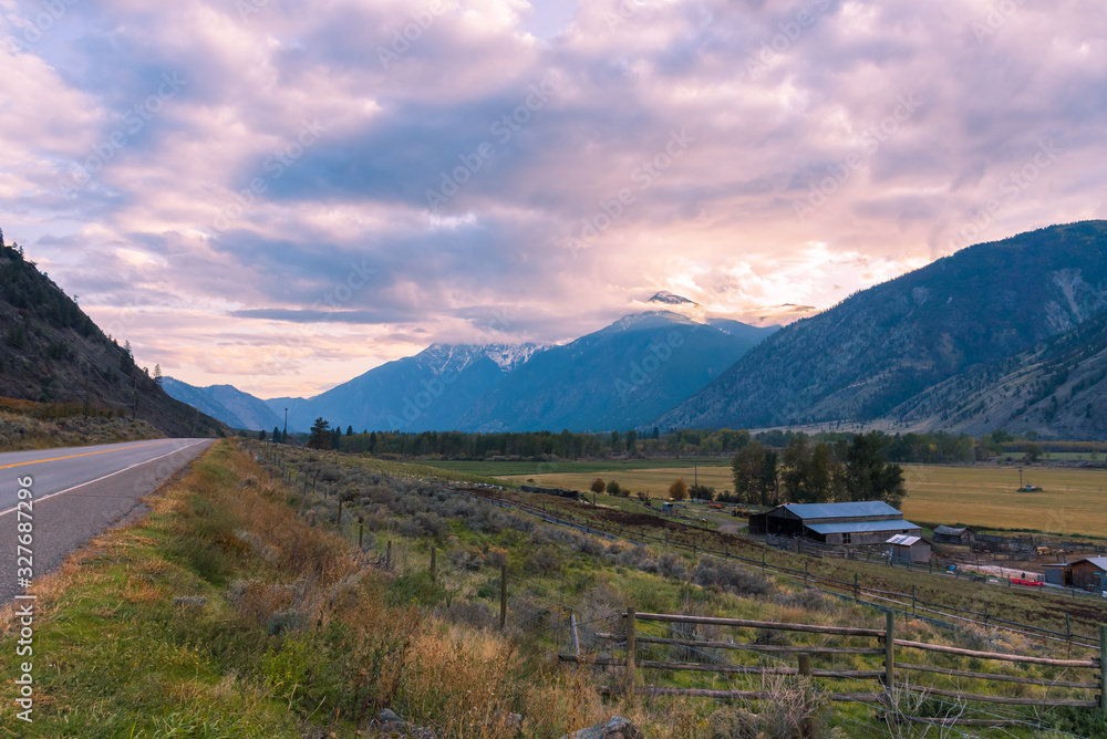 Sunset view of snow-capped mountains, highway, and valley in Cawston, BC, Canada