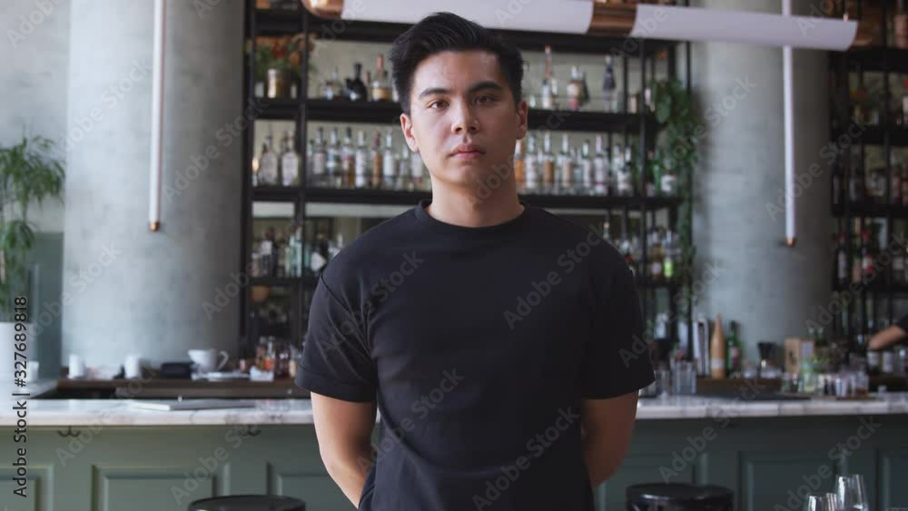 Portrait of male owner of restaurant bar standing by counter looking confident - shot in slow motion Portrait of male owner of restaurant bar standing by counter looking confident - shot in slow motion