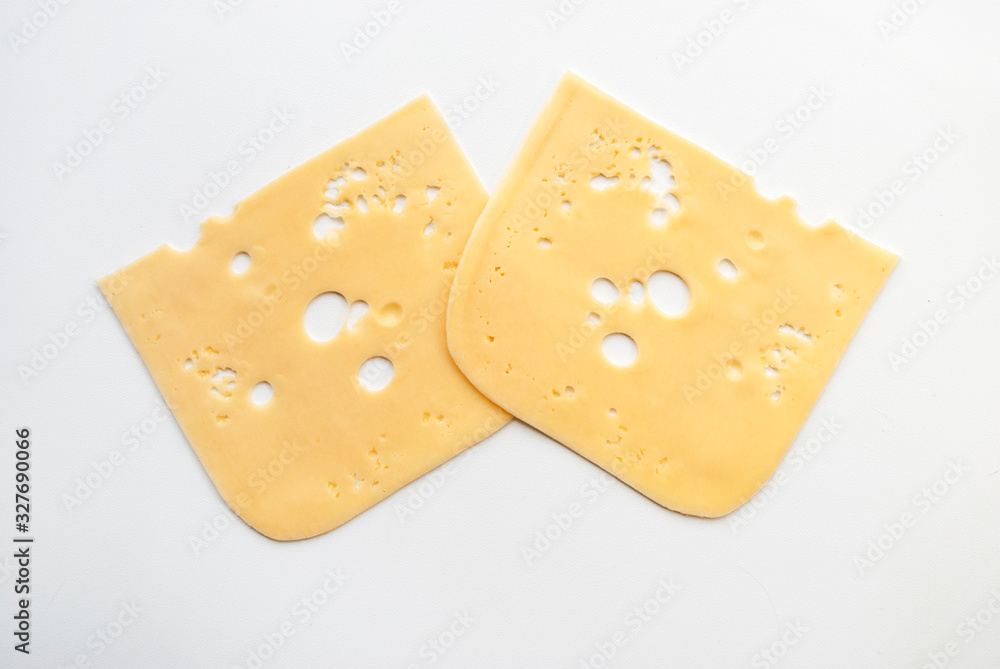 top view close-up of square cheese radamer slices isolated on a white background. Two pieces of swiss cheese. Maasdam - Dutch hard cheese with large holes.