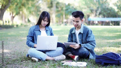 Education study abroad, group of Asian student boy with book and girl sitting at the park talking look at laptop using internet friend connection, businesswoman use computer analysis finance data