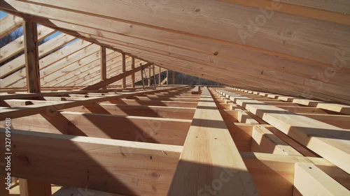 Camera is moving backward, view of the area under wooden roof beams, future attic of the frame house under construction