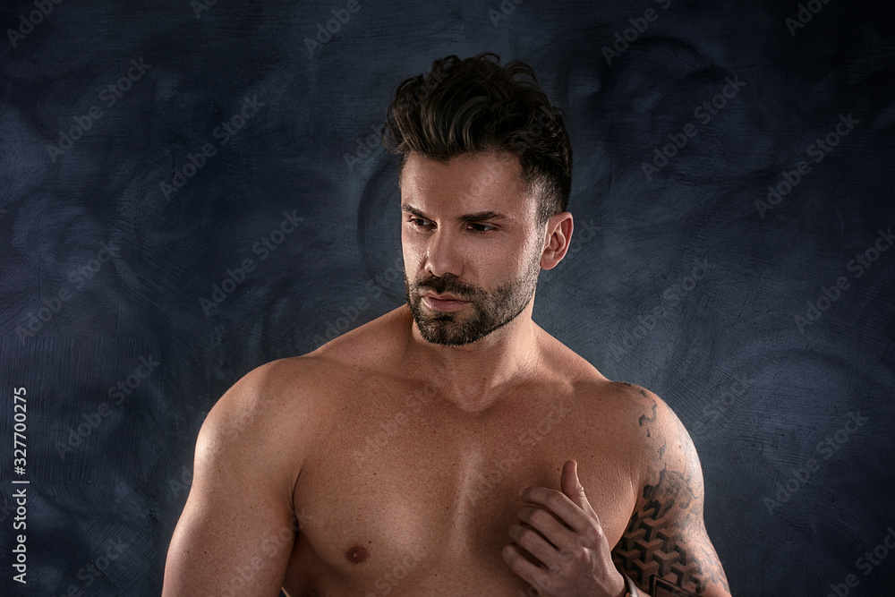Muscular model, brunet man on dark background