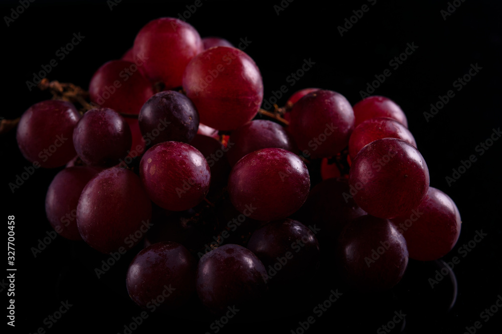 Close-up of blue grapes, on black background, dark with backlight