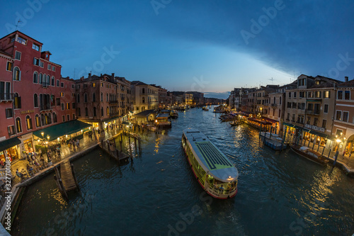 VENICE, ITALY - August 02, 2019: View from Rialto Bridge in Venice at sunset time. Venetian Grand Canal with historical buildings, hotels, tourist boats, piles, berths. Fish eye lens shot © Yury