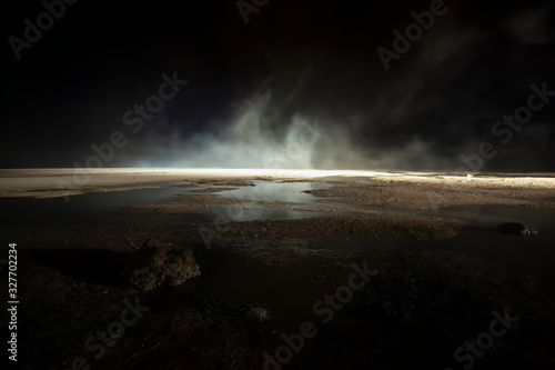 abstract mars like terrain with muddy puddles of water textures, rocks and heavy fog rolling through night background. Mars, Moon, Other world or doomed concepts