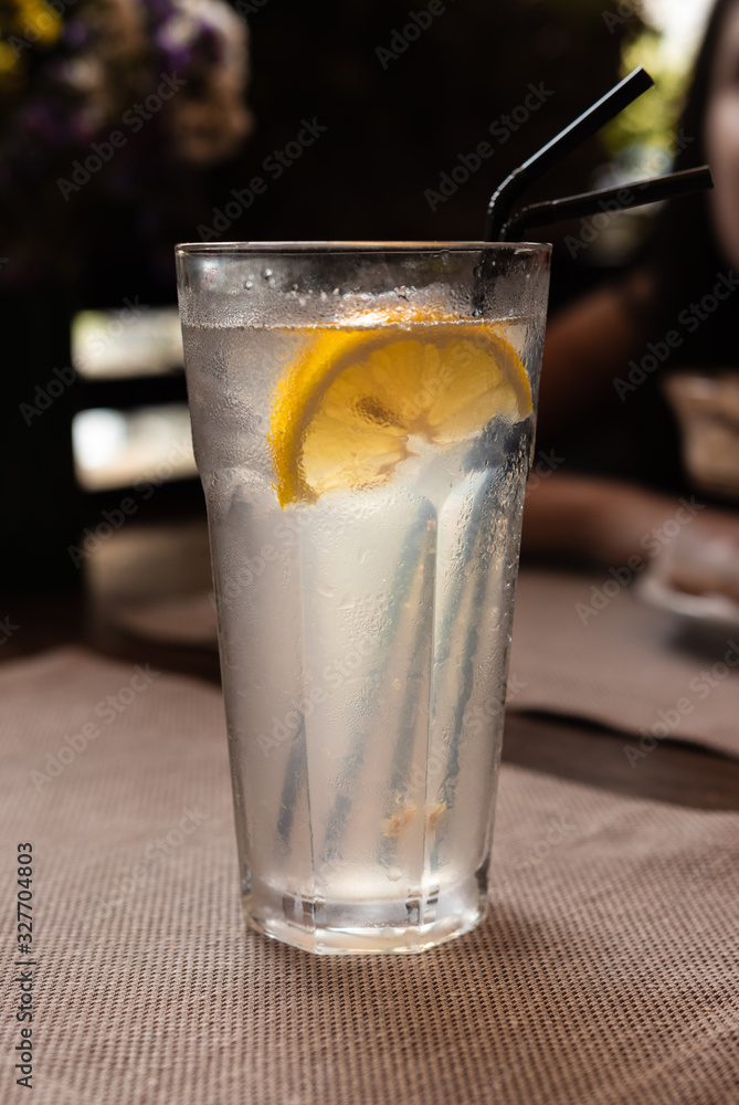 background. transparent glass of lemonade with ice and lemon. black tube in a glass. background. transparent glass of lemonade with ice and lemon. black tube in a glass.