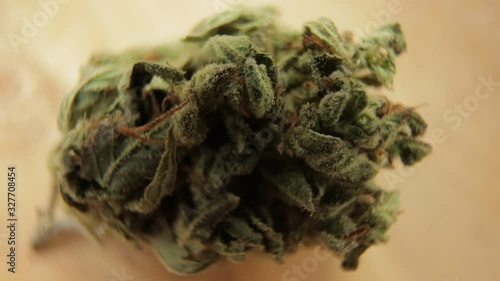 Macro shot of sativa or indica weed bud with fresh trichoma crystals on turning subject wooden table. CBD, THC concept