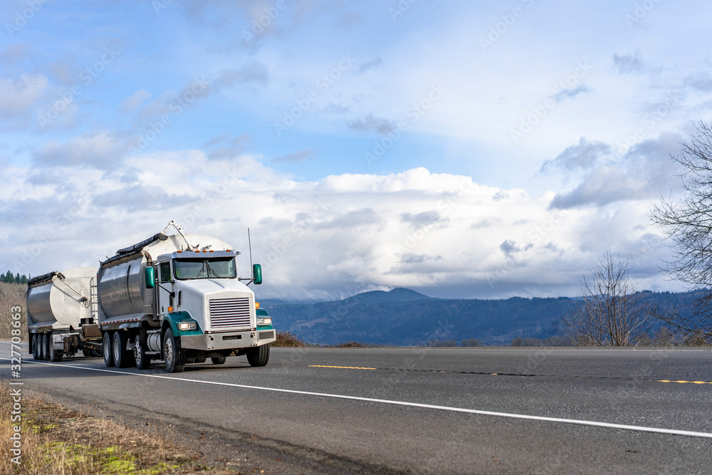 Big rig tip truck with two dump trailers running on the road with mountain and cloud sky view in Columbia Gorge Big rig tip truck with two dump trailers running on the road with mountain and cloud sky view in Columbia Gorge