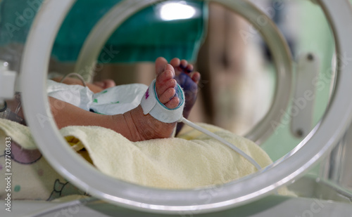 Newborn sick baby in an incubator, selective feet view with blue ink from Footprint. Close up and selective focus