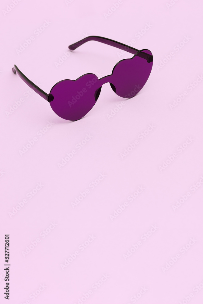 Stylish heart shaped glasses on pink background with copy space. Beautiful trendy purple sunglasses. Fashion summer concept. Stylish heart shaped glasses on pink background with copy space. Beautiful trendy purple sunglasses. Fashion summer concept.