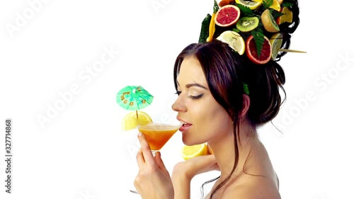 Sip summer martini cocktail in glass by girl. Woman has high hairstyle with fresh fruits as concept summer time. photo