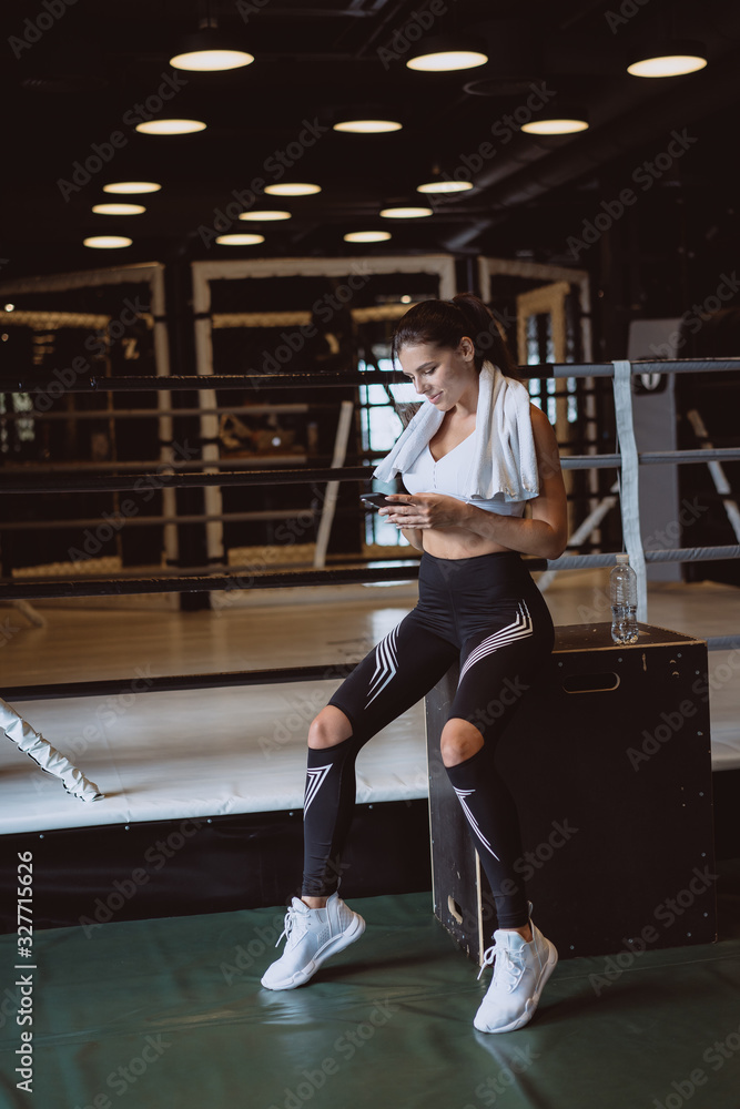 Girl texting while taking a break in a gym. Reads a message Girl texting while taking a break in a gym. Reads a message