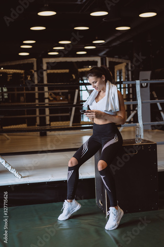 Girl texting while taking a break in a gym. Reads a message