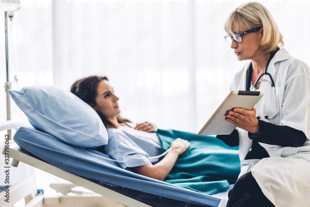 Fototapeta premium Doctor discussing and consulting check up information on tablet computer with female patien on the bed in hospital.healthcare and medicine