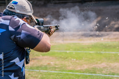 selective focus of man holding and fire shotgun in shooting range of gun shooting competition photo