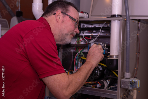 HVAC Tech Making A Repair To Furnace  Red Shirt 