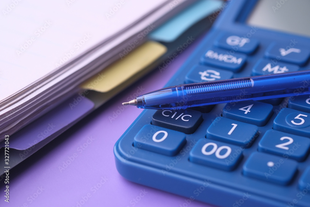 Close up of pen, calculator and notepad on color background Close up of pen, calculator and notepad on color background