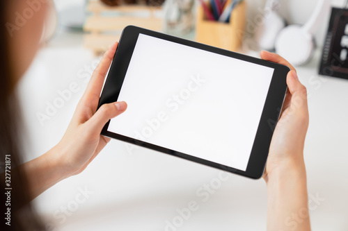 Close-up of hand holding black tablet on table office.