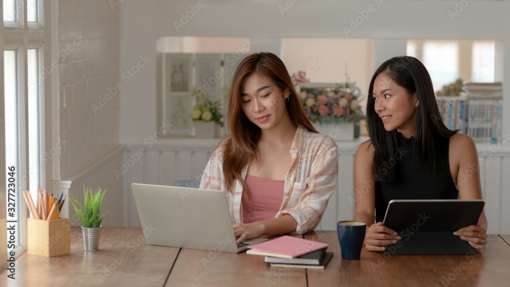 Close up view of two young college girl brainstorming on their assignment with laptop and tablet Close up view of two young college girl brainstorming on their assignment with laptop and tablet