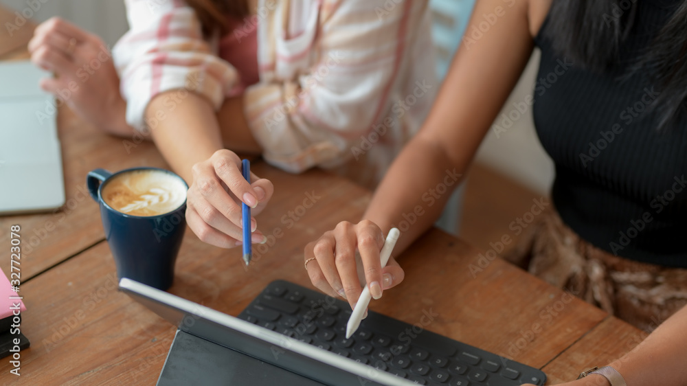 Cropped shot of two college girl consulting on their assignment with digital tablet Cropped shot of two college girl consulting on their assignment with digital tablet