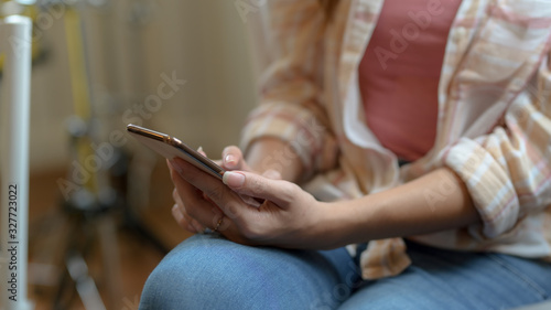 Cropped shot of female using on blank screen smartphone on her lap