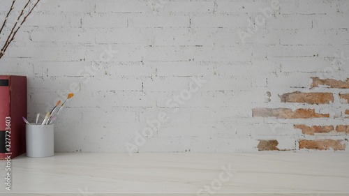 Close up view of minimal workplace with books, painting brush and copy space on marble desk