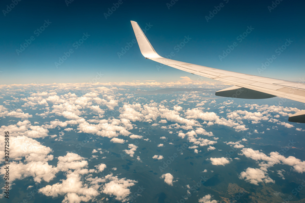 Obraz premium Airplane flying above the clouds at sunset