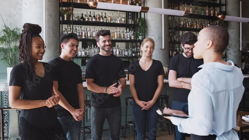 Female restaurant bar manager holding digital tablet giving motivational talk to waiting staff before opening - shot in slow motion