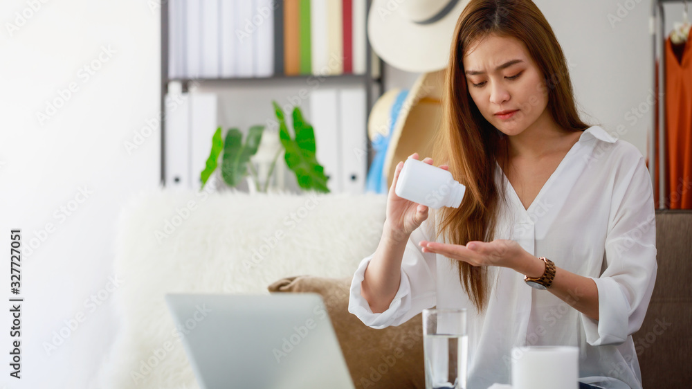 Asian beautiful women stressful and headache after working with a laptop for a long time.Hand holding bottle of headache medicine.Office syndrome concept. Asian beautiful women stressful and headache after working with a laptop for a long time.Hand holding bottle of headache medicine.Office syndrome concept.