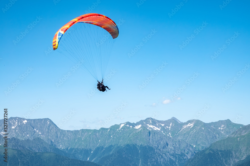 Red paraglider in blue clear sky over the Green Mountain Red paraglider in blue clear sky over the Green Mountain