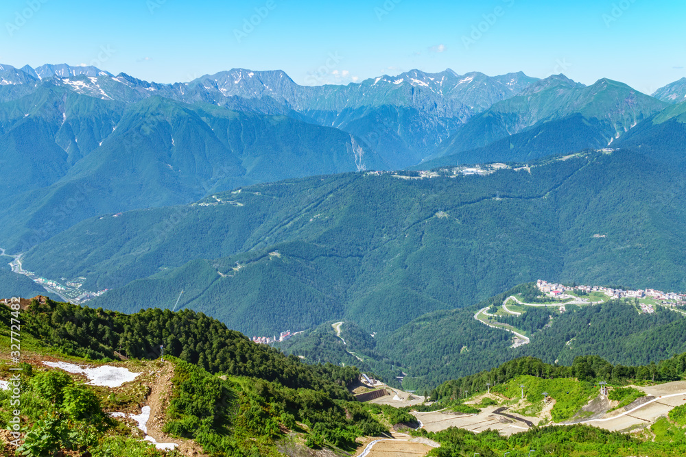 A panoramic view of the Valley with apartment buildings, surrounded by mountains with cable cars.