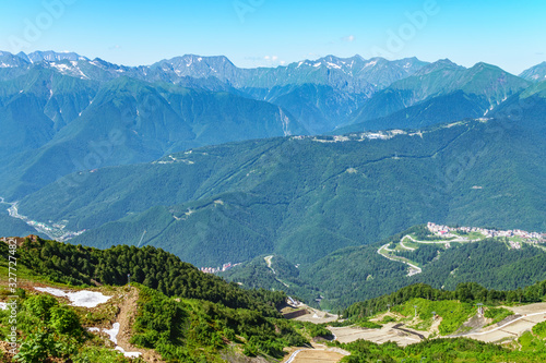 A panoramic view of the Valley with apartment buildings  surrounded by mountains with cable cars.