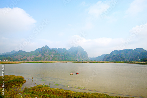 VANLONG NATURAL RESERVE, NINH BINH, VIETNAM - FEBRUARY 29, 2020:  A couple of local people searching for snails underwater on the lagoon. photo