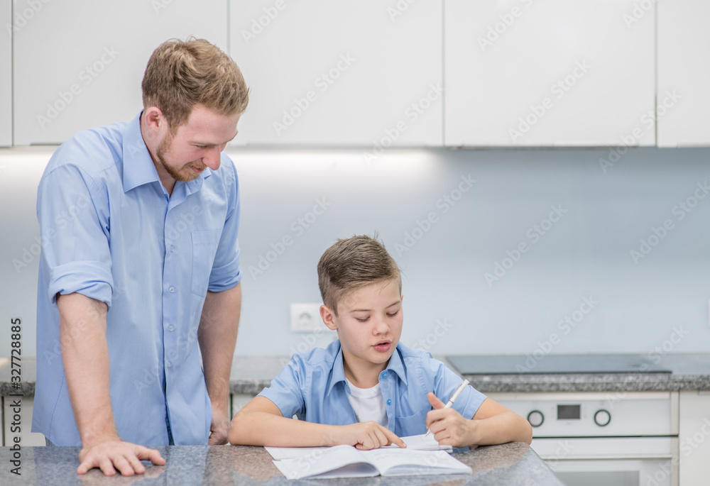 Fototapeta premium Father helps his son doing homework at home. Empty space for text