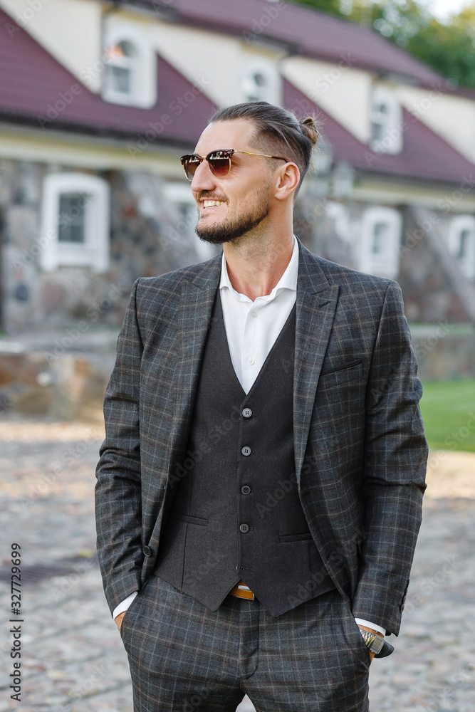 Stylish man in a suit and sunglasses posing in the park Stylish man in a suit and sunglasses posing in the park