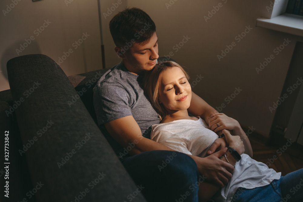 Charming blonde girl lying on her caucasian lover with closed eyes while sitting on a sofa together Charming blonde girl lying on her caucasian lover with closed eyes while sitting on a sofa together