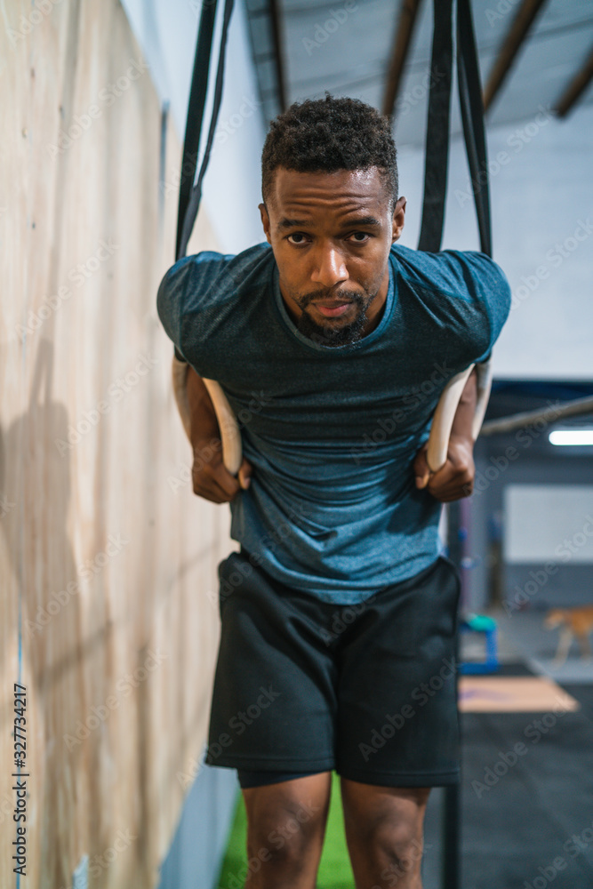 Athletic man working out his muscles on rings.