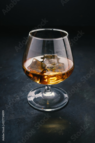Cognac in a glass with ice. Strong alcohol.