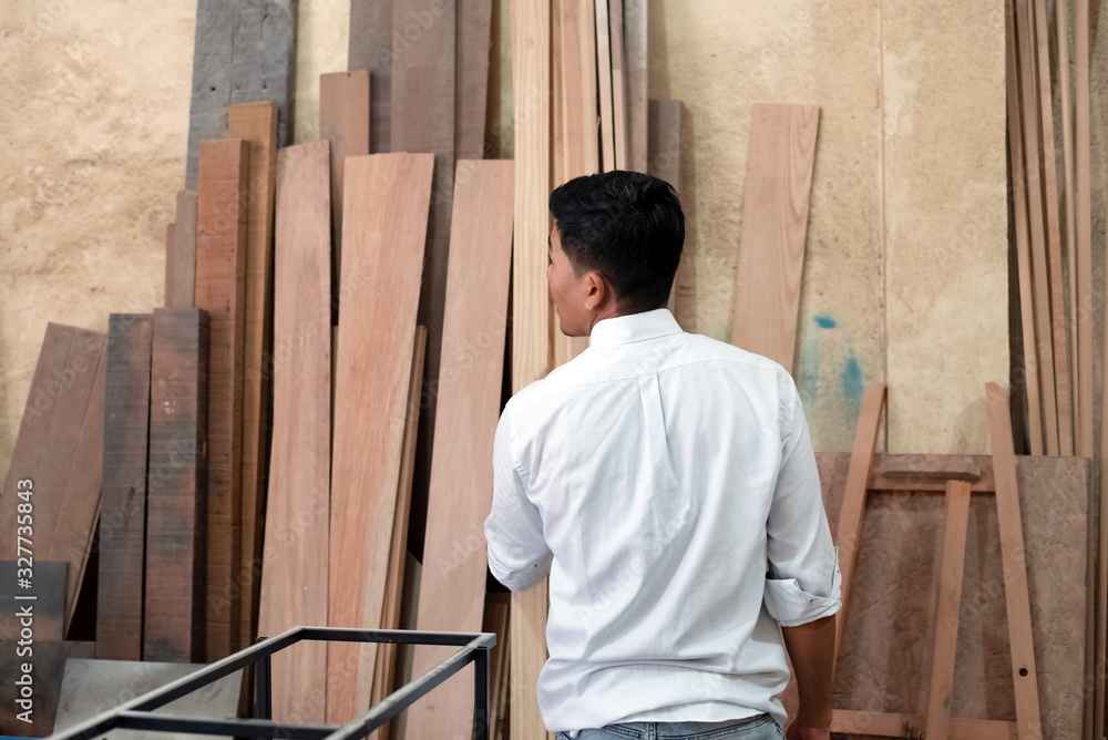 backside of Handsome man standing in front of wood pile, doing wood work at factory,Handmade design backside of Handsome man standing in front of wood pile, doing wood work at factory,Handmade design