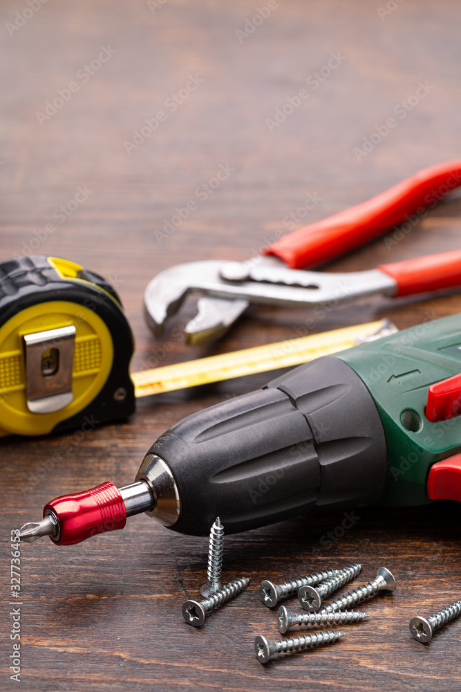 A screwdriver and other household tools for home repair. Studio shot, closeup, brown background. A screwdriver and other household tools for home repair. Studio shot, closeup, brown background.