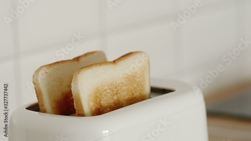 CLOSE UP: Roasted bread in a white toaster