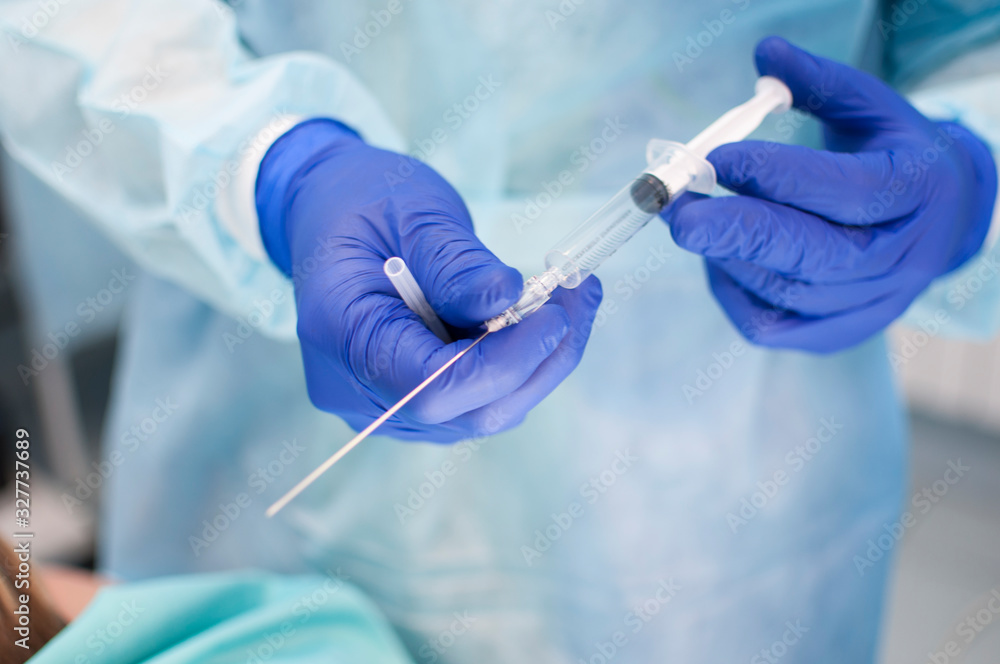 a syringe with a long needle in the hands of a dressed surgeon in the operating room a syringe with a long needle in the hands of a dressed surgeon in the operating room
