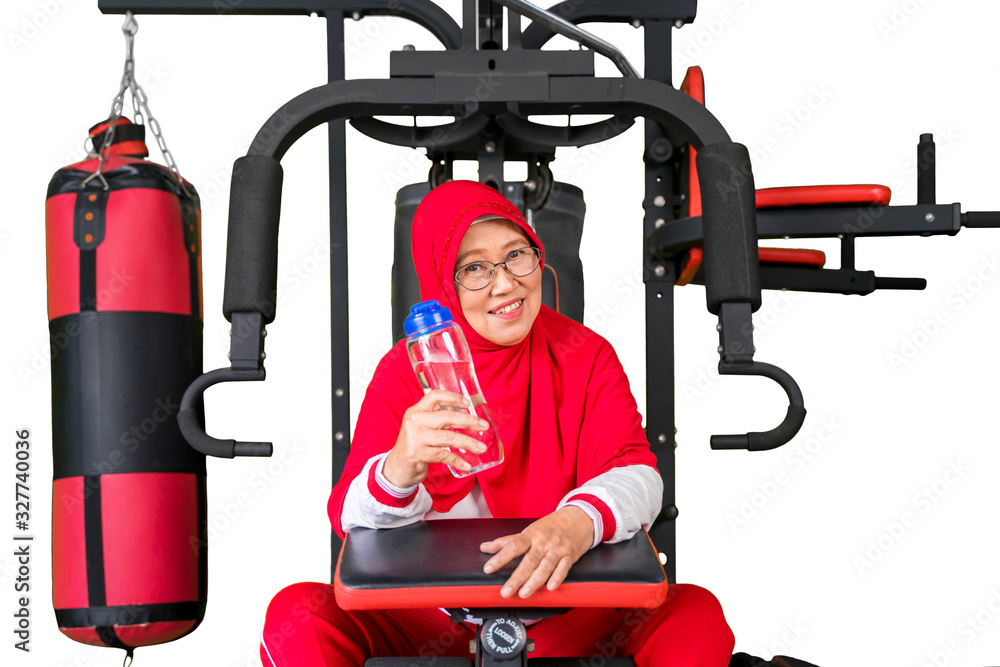 Obraz premium Senior muslim woman sitting on gym machine