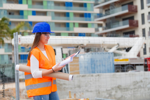 Architecture student checking blueprints next to a construction site