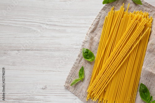 Dry Organic Bucatini Pasta on a white wooden background, top view. From above, flat lay, overhead. Copy space. photo