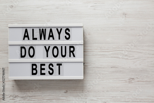 'Always do your best' words on a lightbox on a white wooden background, top view. Overhead, from above, flat lay. Copy space.
