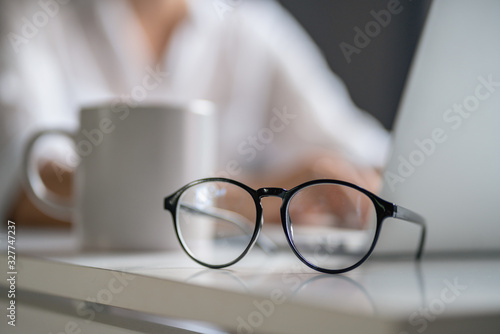 Glasses lie on a table on the background of a man with a computer, vision care concept